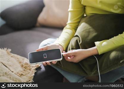 Woman hands Charging mobile phone battery with low battery. plugging a charger in a smart phone with energy bank powerbank power charger Modern lifestyle energy technology concept