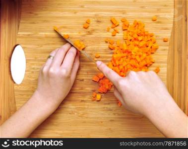 woman hands chopping carrots over wooden hogger