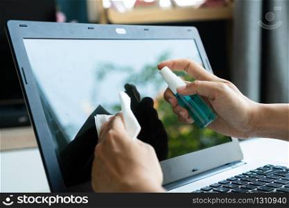 Woman hands cleaning laptop screen with disinfectant wet wipe. Concept of disinfecting surfaces from bacteria or viruses. Close up