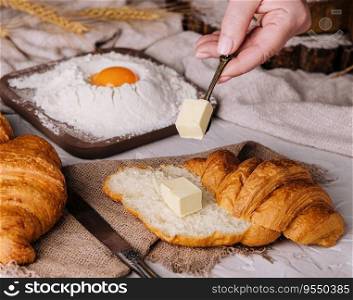 woman hands cut a fresh croissant and spreading butter