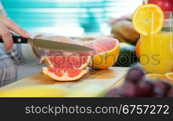 Woman hands cutting grapefruit in the kitchen