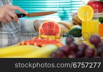 Woman hands cutting grapefruit in the kitchen