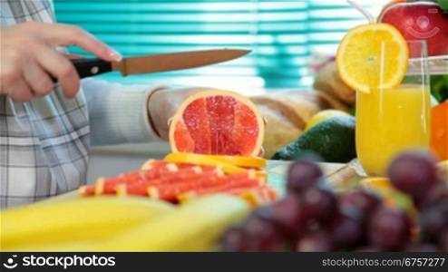 Woman hands cutting grapefruit in the kitchen