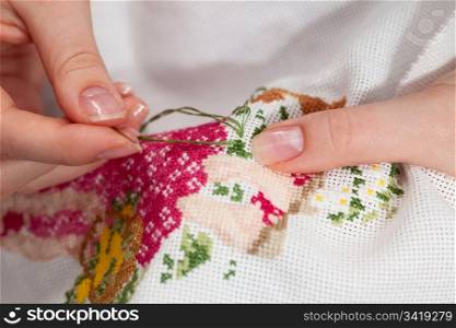 Woman hands doing cross-stitch. A close up of embroidery.