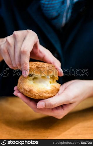Woman hands holding Choux cream. French dessert.