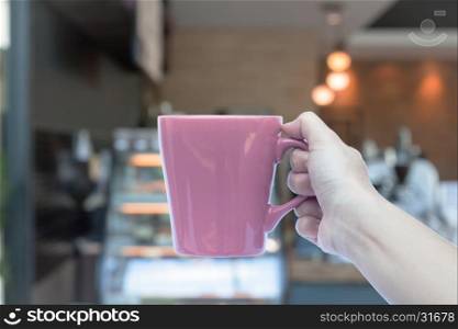 Woman hands holding coffee cup with blurred coffee shop, stock photo
