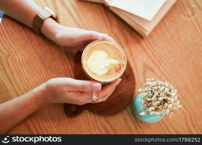 Woman hands holding cup of coffeewith latte art. holding cup of tea or coffee in the morning.