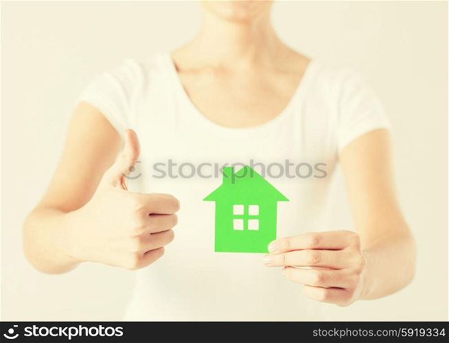 woman hands holding green house showing thumbs up. woman hands holding green house