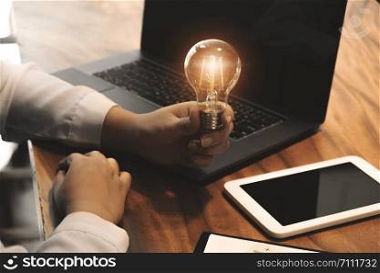 woman hands holding light bulb in working place.