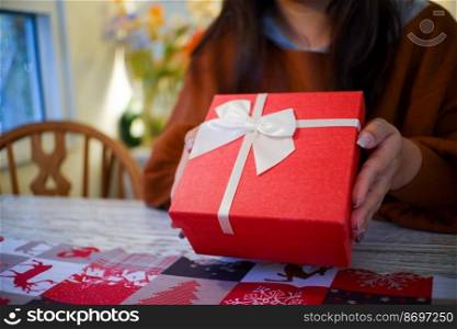 Woman hands holding red gift box.