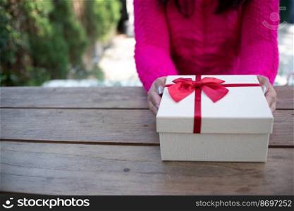 Woman hands holding white gift box.