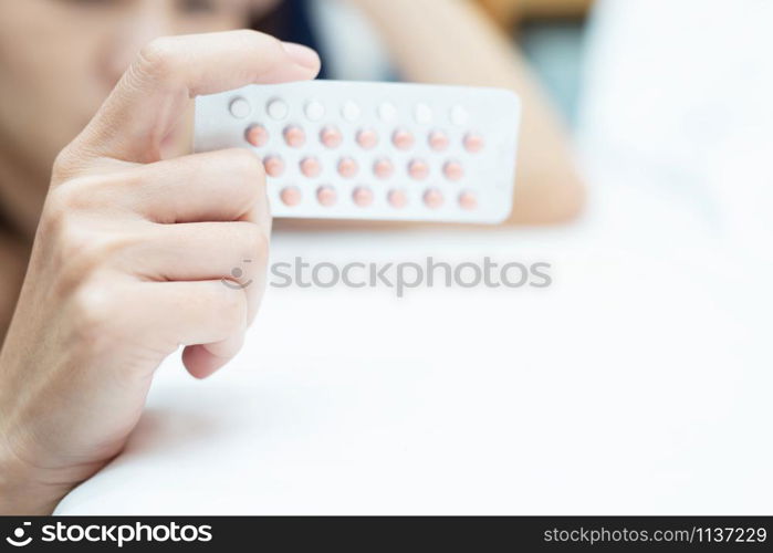 Woman hands opening birth control pills in hand on the bed in the bedroom. Eating Contraceptive Pill.