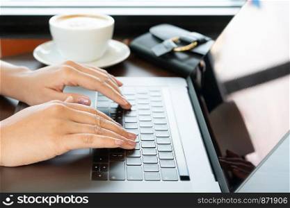 woman hands typing on laptop keyboard. Woman working at office with coffee