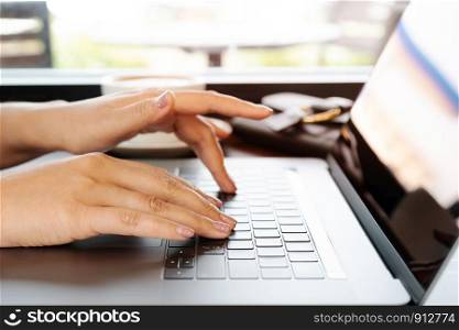 woman hands typing on laptop keyboard. Woman working at office with coffee