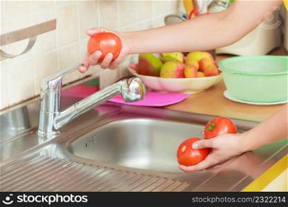 Woman hands washing fresh vegetables tomatoes in kitchen under water stream, preparation salad vegetarian meal