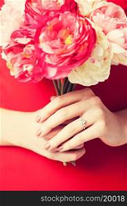 woman hands with bouquet of flowers and wedding ring.