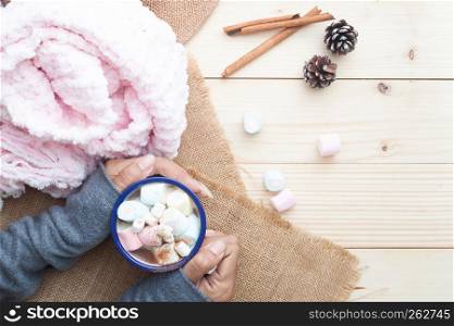 Woman hands with hot chocolate with pastel colour marshmallows on top. Cozy lifestyle. Winter concept