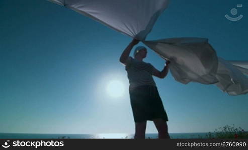 Woman hanging white laundry on washing line in the wind