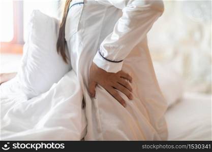 woman have a back and hip pain sitting on bed in bedroom feeling painful,Healthcare concept