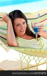 Woman having a cocktail drink in a hammock