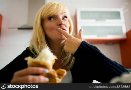 Woman having a croissant as breakfast in her kitchen