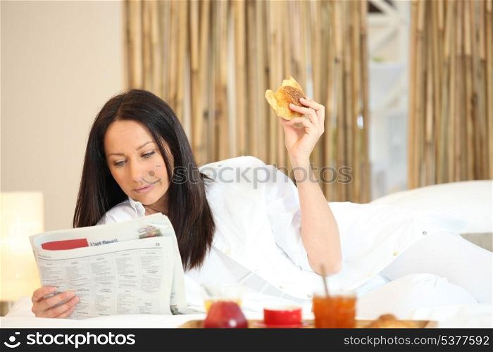 Woman having breakfast and reading newspaper