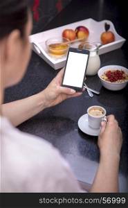 woman having breakfast while using smartphone