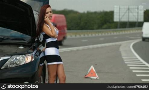 Woman having car troubles on the road, calling on the cell phone for emergency repair service