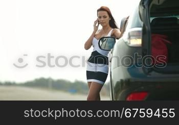 Woman having car troubles on the road, calling on the cell phone for emergency repair service