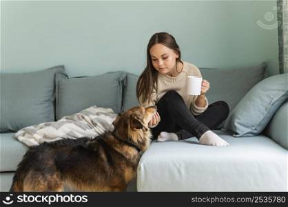 woman having coffee home with her dog during pandemic