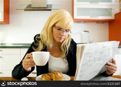 Woman having coffee, reading the morning newspaper