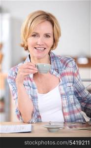 Woman having cup of coffee at kitchen table