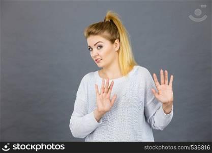 Woman having disgust face expression seeing unpleasant thing deny something showing stop gesture with open hands, grey background.. Woman deny something showing stop gesture with hands