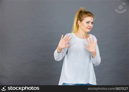 Woman having disgust face expression seeing unpleasant thing deny something showing stop gesture with open hands, grey background.. Woman deny something showing stop gesture with hands