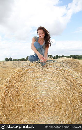 Woman having fun sitting on hay bale