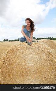 Woman having fun sitting on hay bale