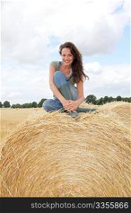 Woman having fun sitting on hay bale