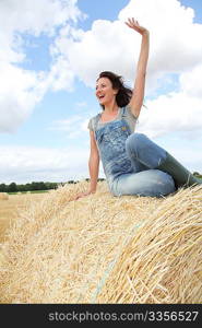 Woman having fun sitting on hay bale