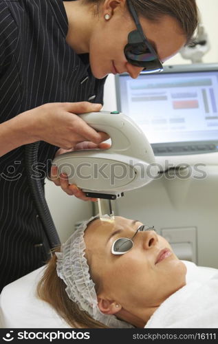 Woman having laser facial treatment in salon