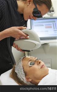 Woman having laser facial treatment in salon