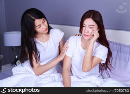 woman having problem and woman cheers her up on bed in the bedroom