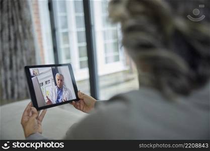 Woman Having Remote Consultation With Doctor At Home Using Digital Tablet