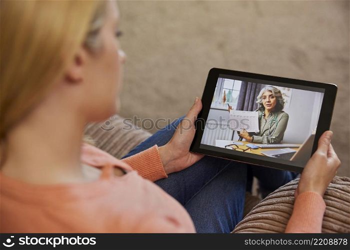 Woman Having Remote Consultation With Female Doctor At Home Using Digital Tablet