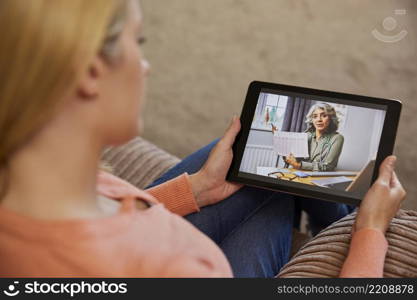 Woman Having Remote Consultation With Female Doctor At Home Using Digital Tablet