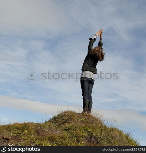 Woman having standing stretch on hilltop