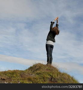 Woman having standing stretch on hilltop