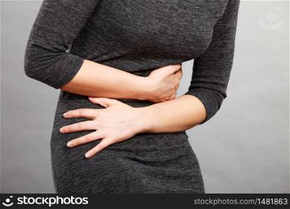 Woman having strong stomach ache. Syndroms of indigestion pregnancy. Female suffer on belly pain, holds hands on abdomen, part of body on grey. Woman having strong stomach ache. Syndroms