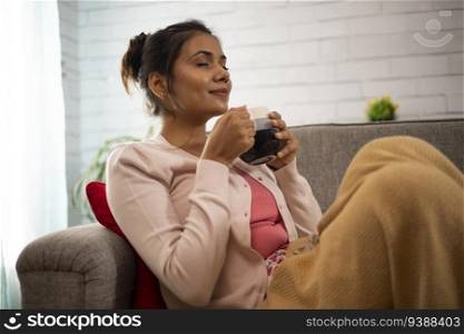 Woman having tea while relaxing on sofa at home