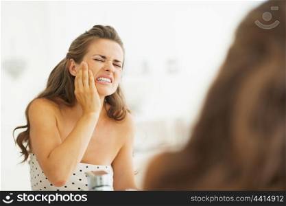 Woman having toothache in bathroom