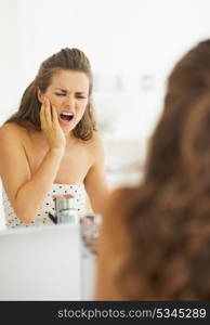 Woman having toothache in bathroom